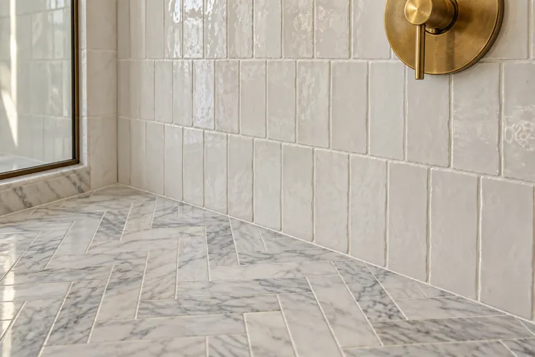White glazed wall tile above a marble herringbone floor